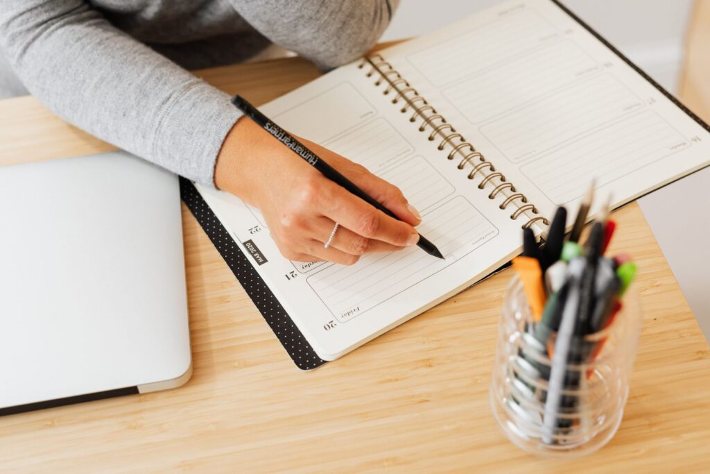 Hand writing in a planner on a wooden desk